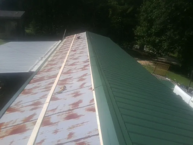 Old rusted panels beside newly installed green metal roofing — Wind Damage Roof Repair by Roofing Brothers in Walnut