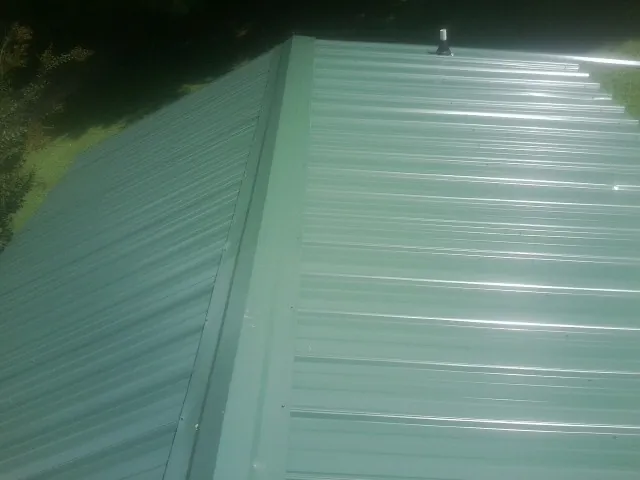 New green metal panels meeting at the ridge of a roof — Flat Roof Repair work by our crew in Walnut