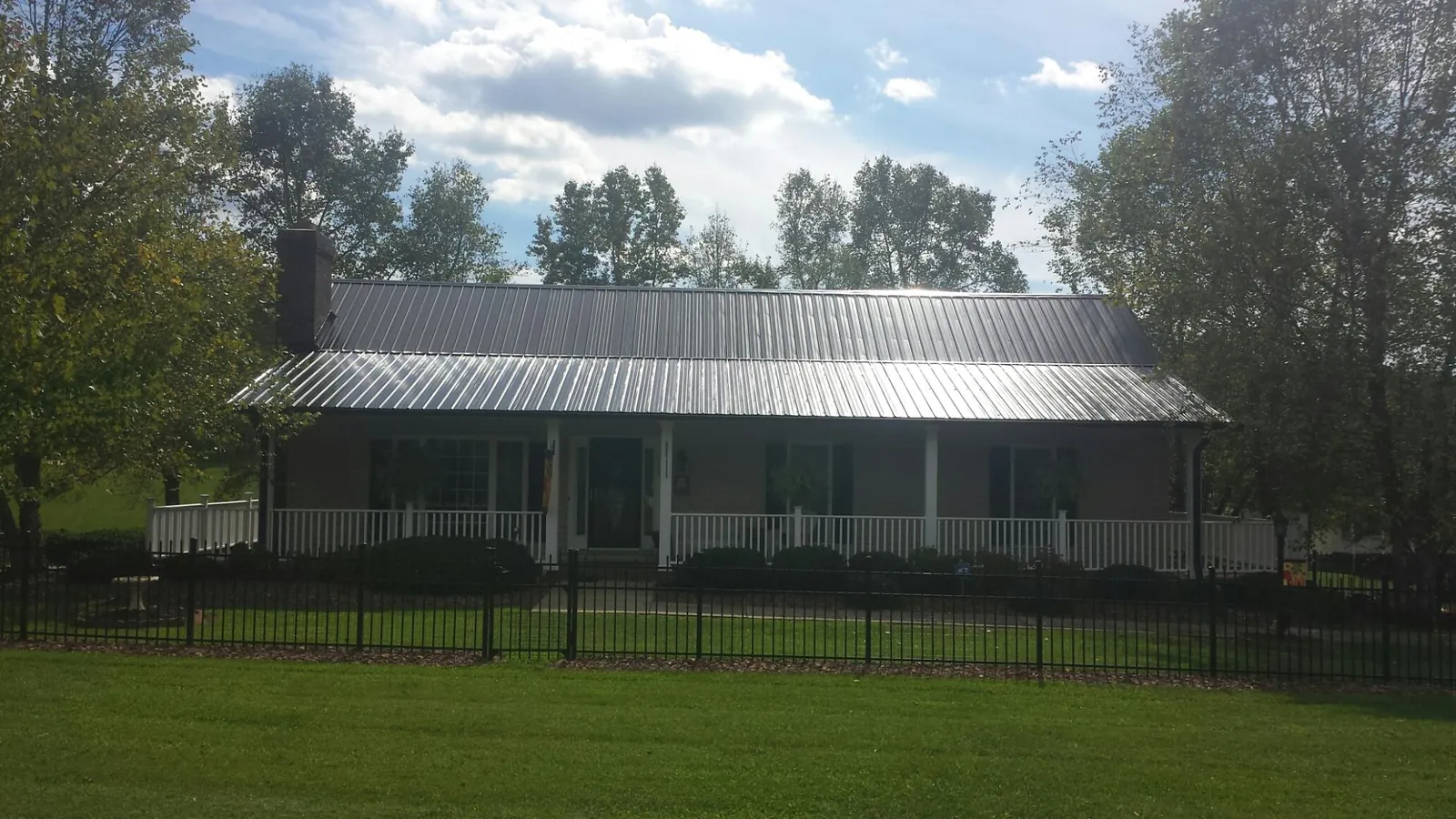 Gray metal roof on a brick ranch with a full width front porch — Gutter Guard Installation work by our crew in Walnut