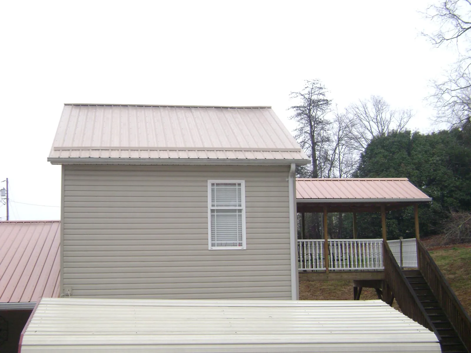 Tan metal roofs on a two story addition and attached porch, from a Roof Replacement job in Walnut